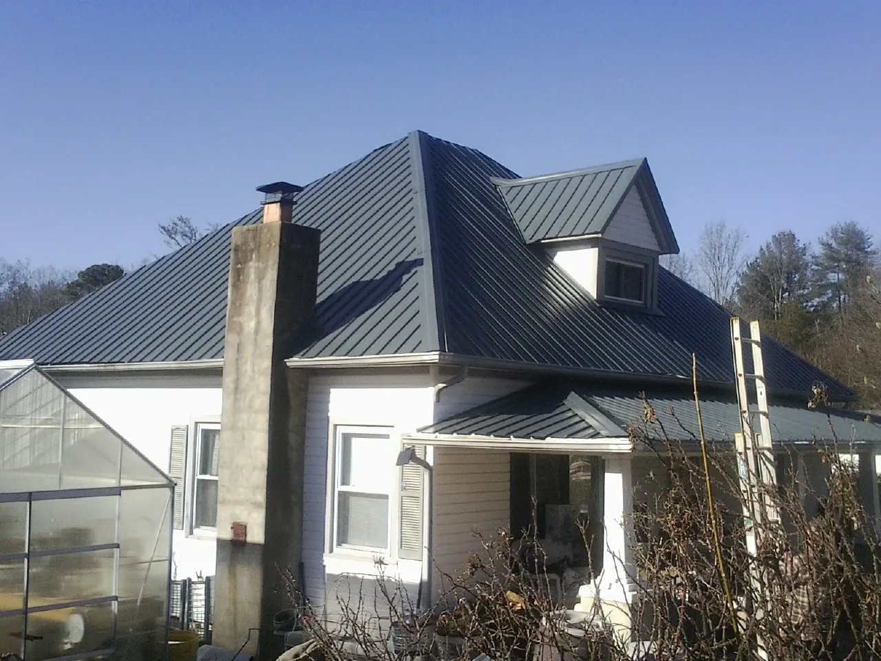 Dark blue standing seam metal roof on a white farmhouse with dormer — Slate & Tile Roof Repair by Roofing Brothers in Shiloh
