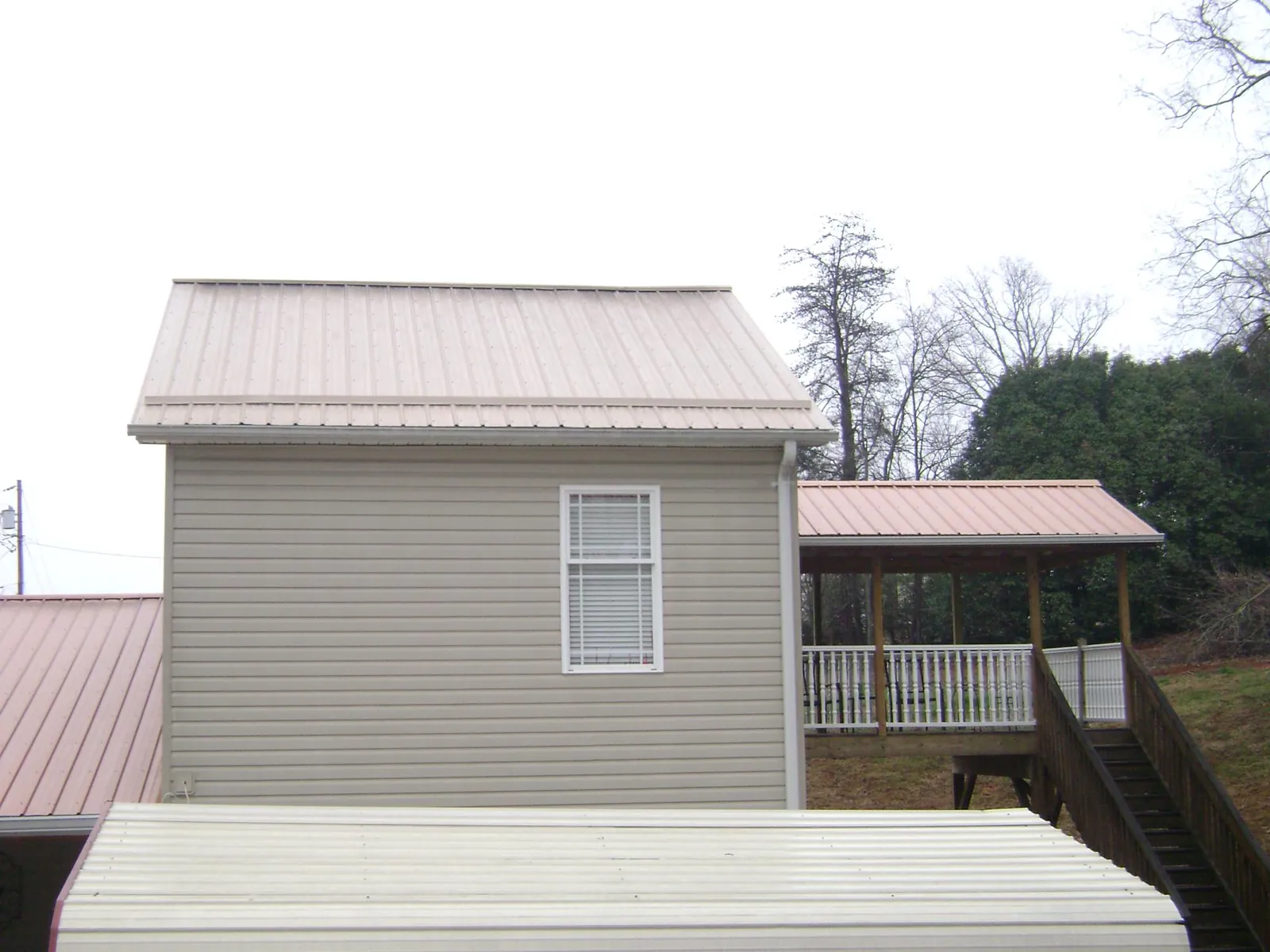Tan metal roofs on a two story addition and attached porch, from a Roof Replacement job in Shiloh