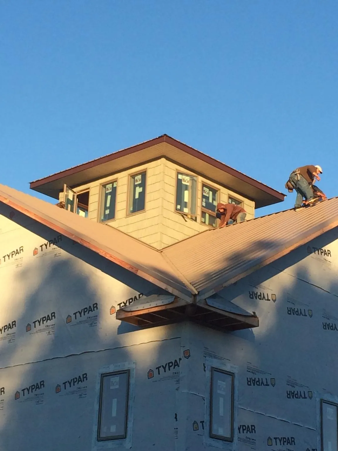 Roofers working around a rooftop cupola on a new metal roof at sunset — Roof Waterproofing in Shiloh by Roofing Brothers